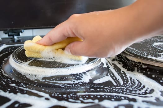Close up of woman cleaning cooker at home kitchen
