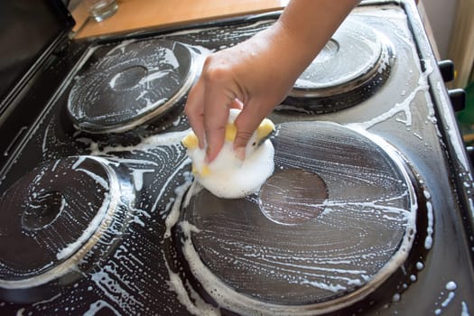 Close up of woman cleaning cooker at home kitchen