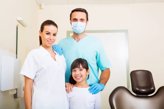 A dentist with his assistant taking care of a little girl..