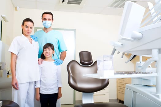 A dentist with his assistant taking care of a little girl..
