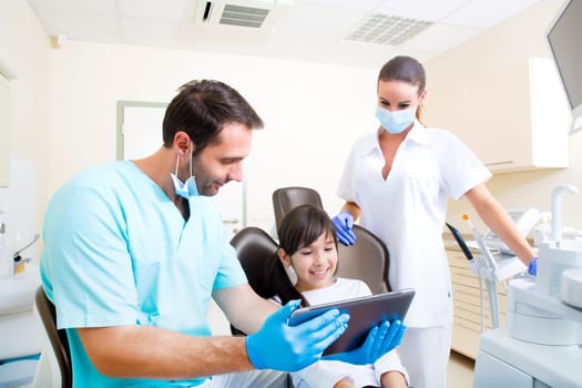 A little girl at the dentist getting a explanation with a Tablet PC..
