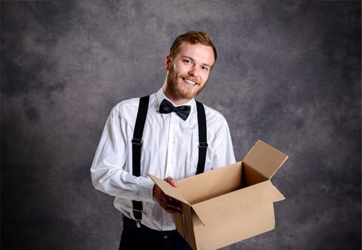 young man opening a package in front of gray background