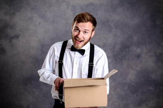 young man opening a package in front of gray background
