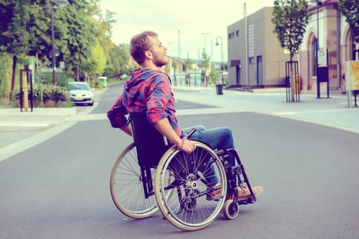 young disabled man in wheelchair on road