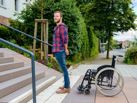young man standing with wheelchair in front of stairs