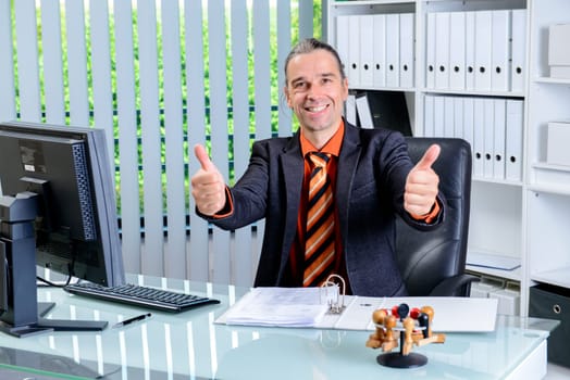 young business man at his desk with thumbs up