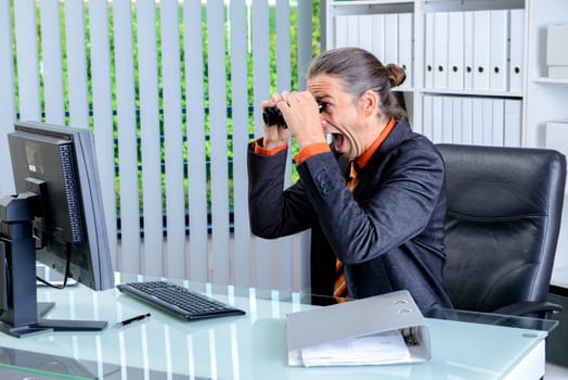young amazed business man looking with binoculars at the screen