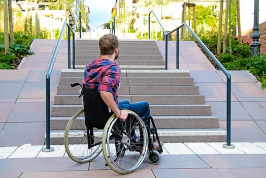 young disabled man in wheelchair in front of stairs