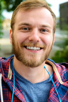 young bearded man in checkered shirt smiling in to the camera