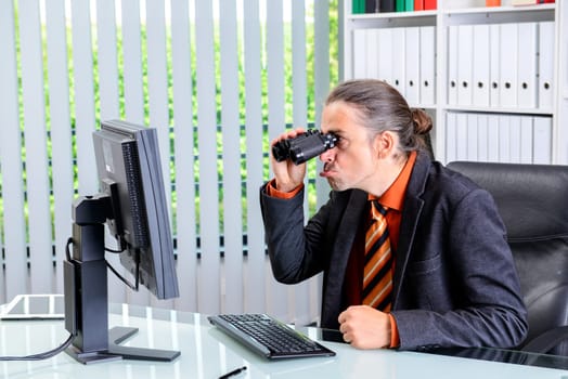 young amazed business man looking with binoculars at the screen