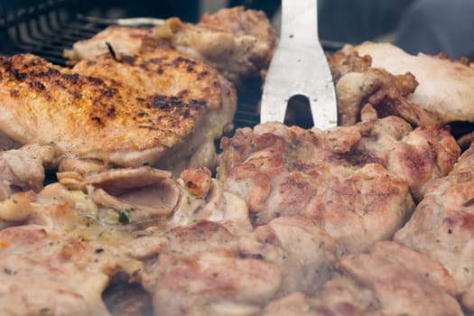 Turning over grilled pork chops. Smoke rising from heated grill