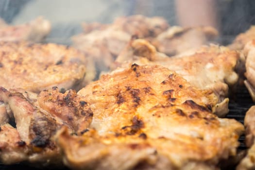 Turning over grilled pork chops. Smoke rising from heated grill