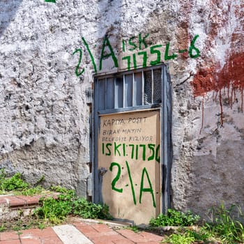 A weathered metal door stands against a textured wall in Istanbul's Balat District, Istanbul, Turkey