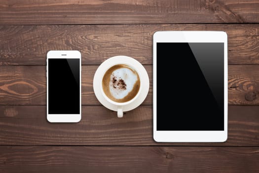 white phone tablet and coffee cup on wood table top view