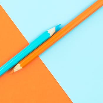 Orange and Turquoise coloured pencils and paper, abstract contrast conceptual image