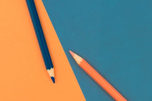Orange and Dark Blue coloured pencils and paper, abstract contrast conceptual image