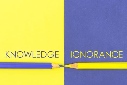 Knowledge versus Ignorance contrast concept . Yellow and Violet coloured pencils and paper.
