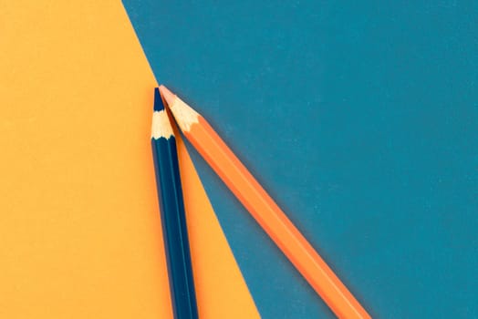 Orange and Dark Blue coloured pencils and paper, abstract contrast conceptual image