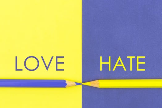 Love versus Hate contrast concept . Yellow and Violet coloured pencils and paper.