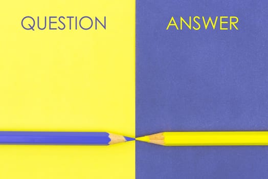 Question versus Answer contrast concept . Yellow and Violet coloured pencils and paper.