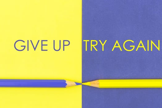 Give Up versus Try Again contrast concept . Yellow and Violet coloured pencils and paper.