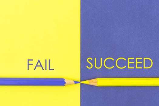 Fail versus Succeed contrast concept . Yellow and Violet coloured pencils and paper.