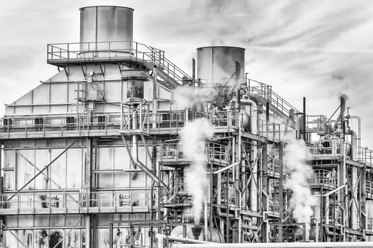 Chemical plant of a factory. Smokestacks ,pipes and tank. Black and white