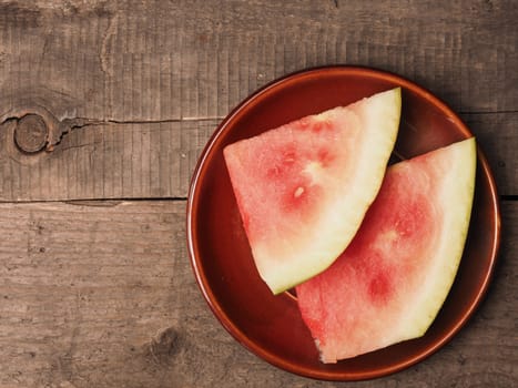 Slices of fresh watermelon on a brown plate with space for text or image