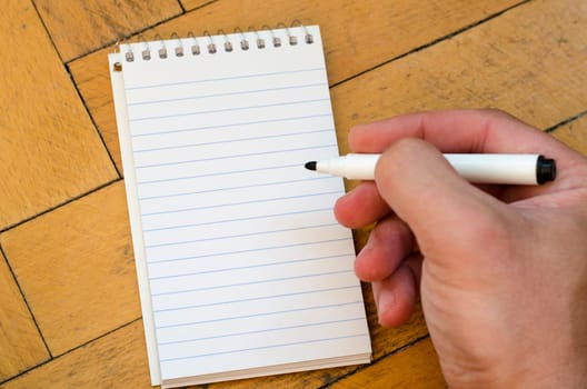 White notepad and human hand on the wooden background