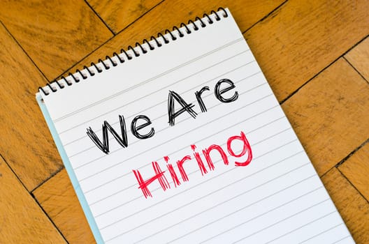 We are hiring text concept on notebook over wooden background