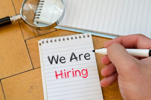 We are hiring text concept on notebook over wooden background