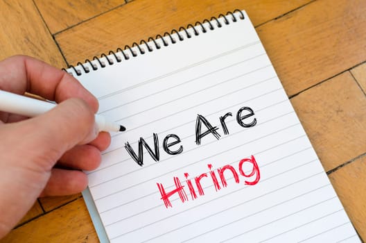 We are hiring text concept on notebook over wooden background