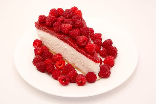 Cheesecake slice with raspberries on a white plate isolated on a white background