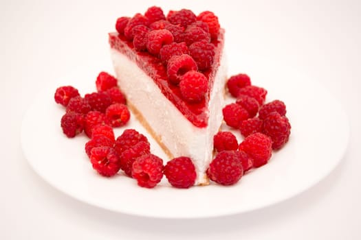 Cheesecake slice with raspberries on a white plate isolated on a white background