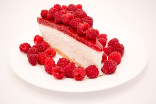 Cheesecake slice with raspberries on a white plate isolated on a white background