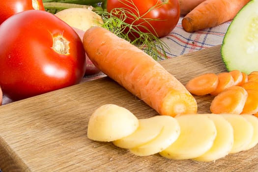 Sliced vegetables on a wooden plate in the kitchen