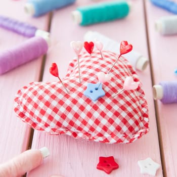 Heart-shaped pincushions with colorful yarns and buttons