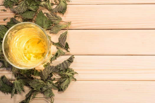 Glass of nettle tea. Table is covered with dry leaves.