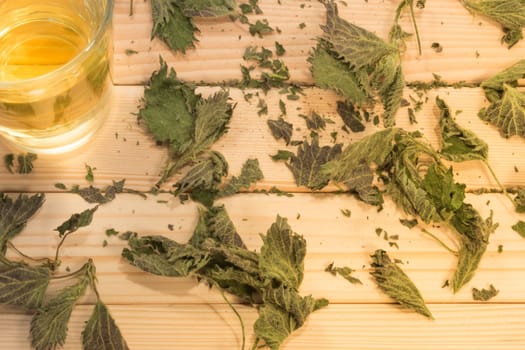 Glass of nettle tea. Table is covered with dry leaves.