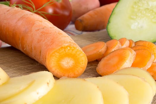 Sliced vegetables on a wooden plate in the kitchen