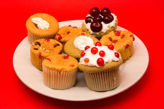 Fruit cupcakes on a plate isolated on red background
