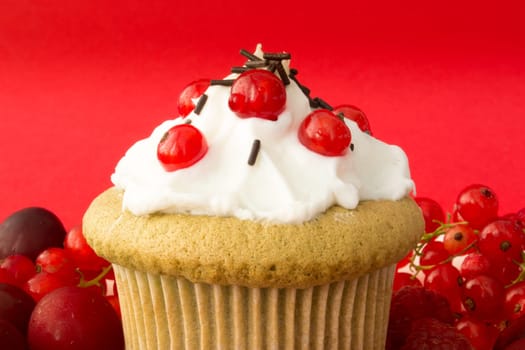 Sweet cupcake with red berries, cherrries and chocolate crumbs on a plate