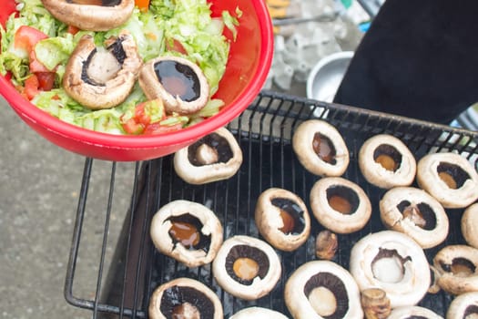 Ball filled up with fresh salad and grilled mushrooms. Barbecue visible in the background