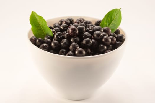 White bowl full with fresh and tasty aronia