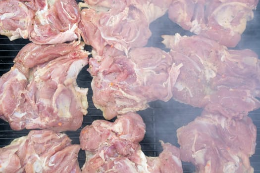 Raw pork chops on grill. Smoke rising from heated grill
