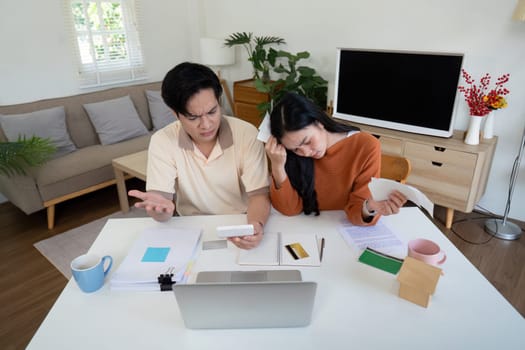 A concerned couple faces financial challenges as they calculate bills and income, expressing frustration and worry together.