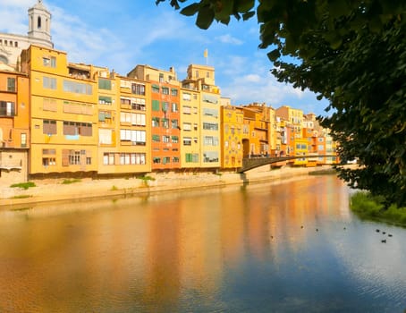 Colorful yellow and orange houses reflected in water river Onyar, in Girona, Catalonia, Spain.