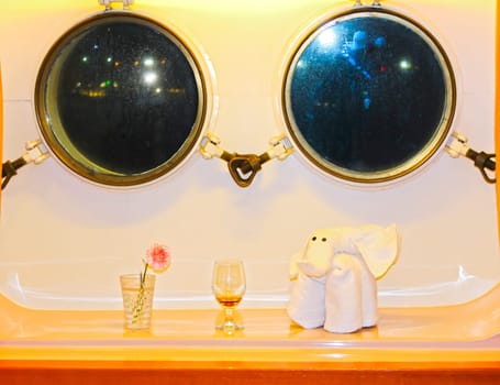 The figure of the towel against two windows in the cabin of a cruise ship