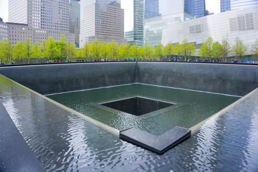 New York CITY, United States of America - May 01, 2016: New York City, Memorial at Ground Zero, Manhattan, commemorating the terrorist attack of September 11, 2001. Flowers near the names of victims engraved in the bronze parapet.