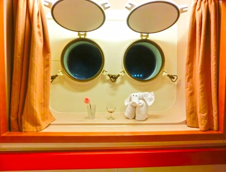 The figure of the towel against two windows in the cabin of a cruise ship